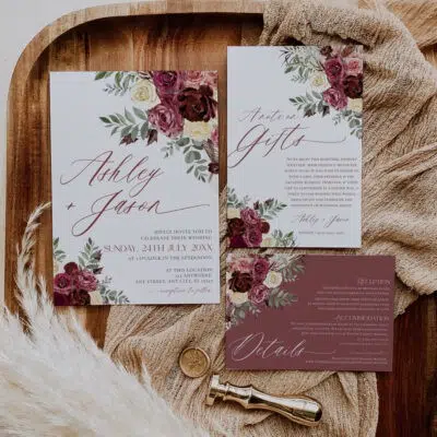 Printable burgundy wedding invitation card featuring burgundy flowers, cream blooms, and rustic greenery leaves. Elegant fall wedding design.